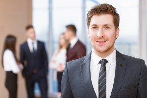 Young business man standing in front of his co-workers talking