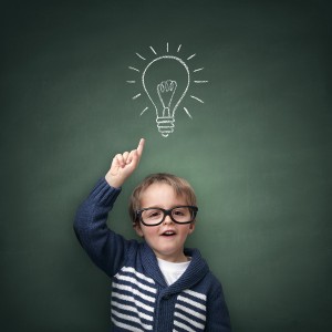 Schoolboy standing in front of a blackboard with a bright idea l