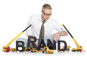 Build up a brand concept: Smiling businessman building the word